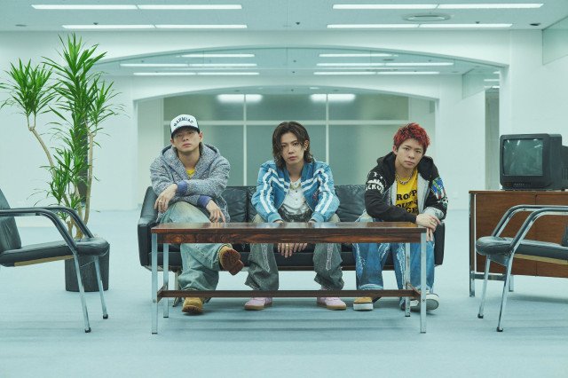 Number_iの新曲BUGS LIFEのミュージックビデオより、神宮寺勇太ら3人がオフィス空間のソファに座る場面