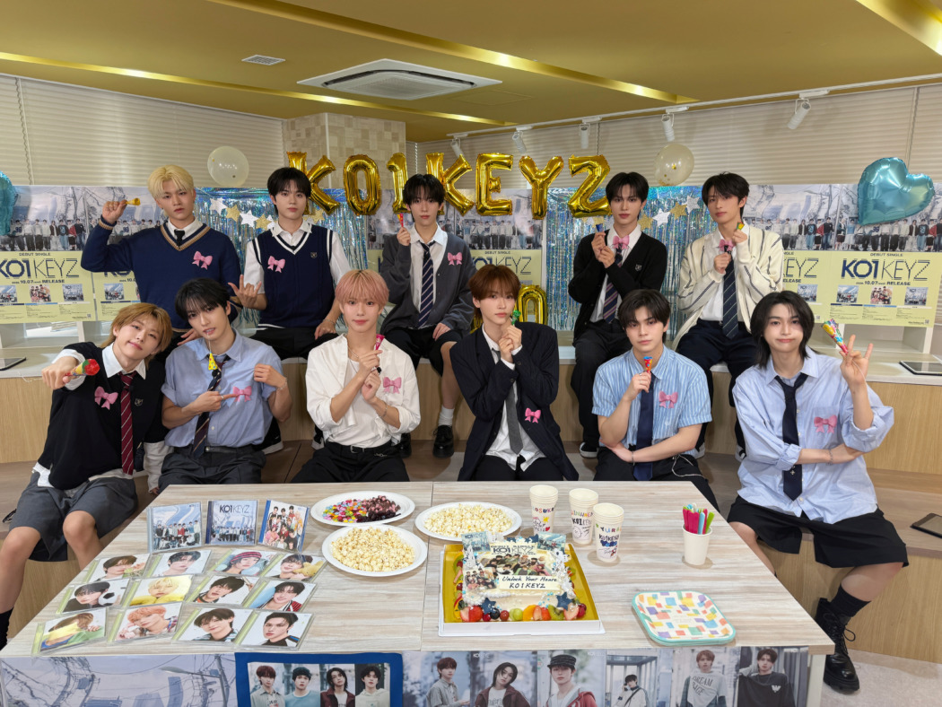 KO1KEYZメンバーがデビュー記念の特典会場でケーキを囲んで祝う様子